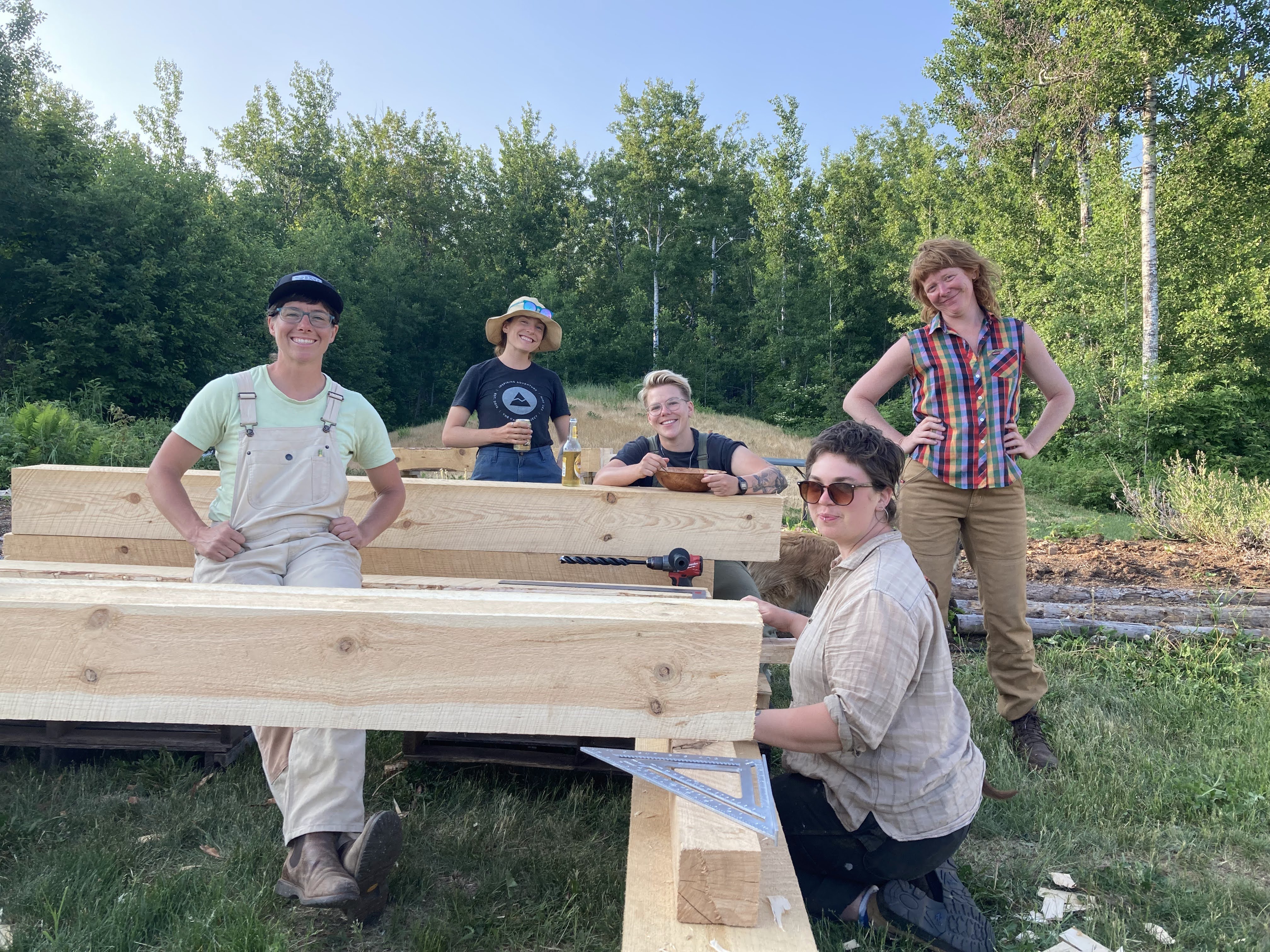 The two Founders of Against The Grain - Jenna Pollard and Helen Prüfer - taking a break on a timber frame with students of the women's timber framing course.